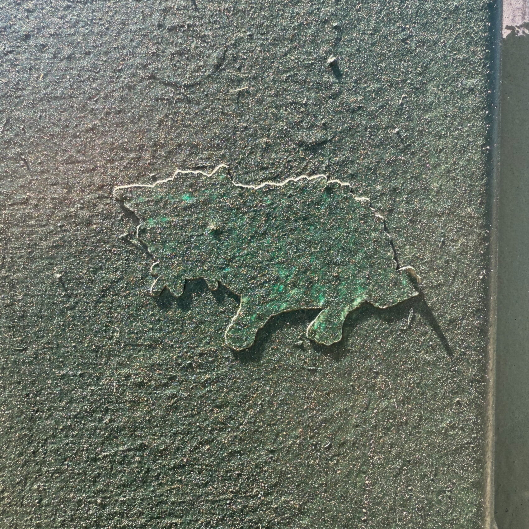 A sticker on a public surface that's been painted over.