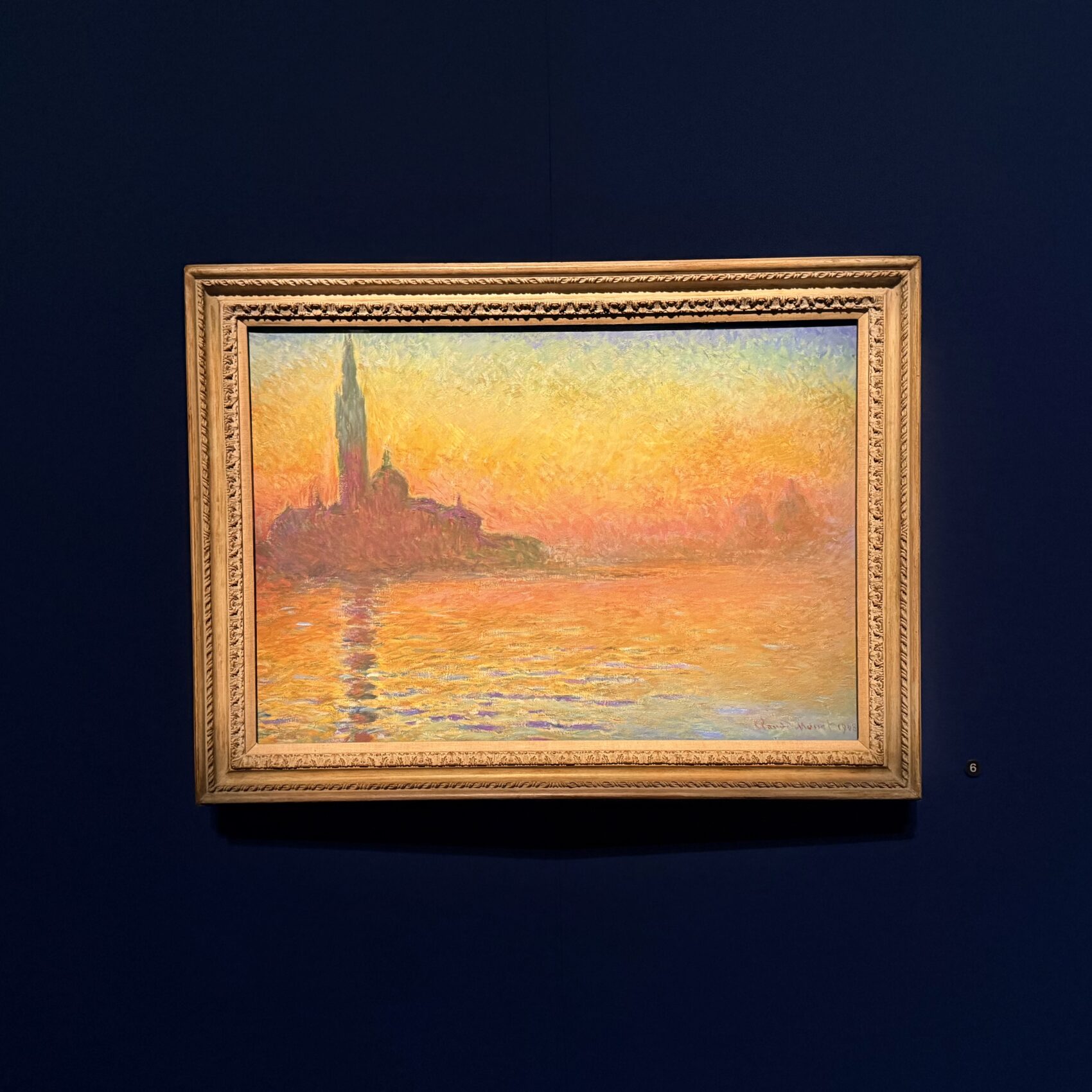 Photo of a framed painting of a rich sunset in the impressionist style