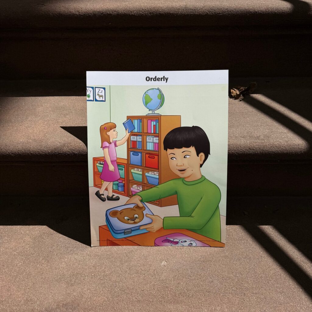 A drawing titled "Orderly" from a children's book of a child closing a small case while another child puts a book away. 